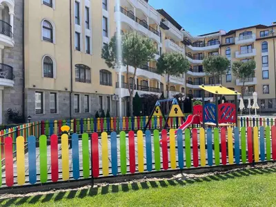 a colorful fence with a playground in front of a building at Royal Sun SP apartments in Sunny Beach