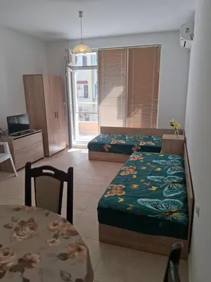 a hotel room with two beds and a table and a table and a tableablish at Dobi Apartments in Pomorie