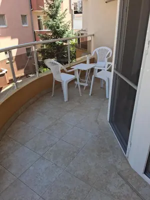 a patio with white chairs and a table on a balcony at Dobi Apartments in Pomorie