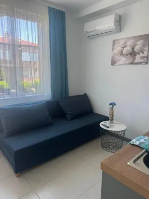 a blue couch in a living room with a window at Апартаменти Лилия 2 in Primorsko