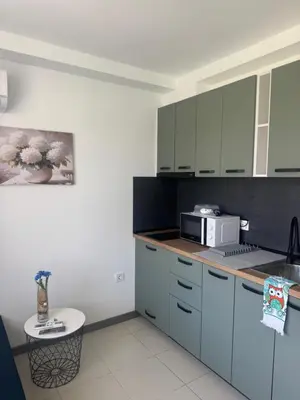 a kitchen with blue cabinets and a microwave at Апартаменти Лилия 2 in Primorsko