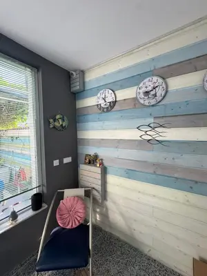 a room with two clocks on the wall and a chair at Апартаменти Лилия 2 in Primorsko