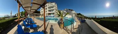 a swimming pool with blue chairs next to a building at White Cliffs первая линия in Byala