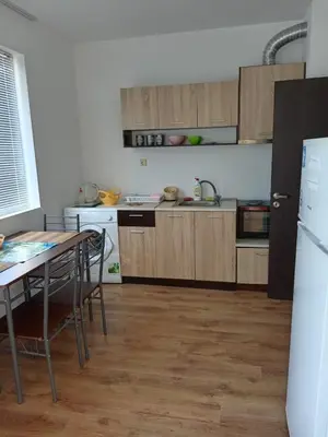a kitchen with wooden cabinets and a table and a refrigerator at Апартаменты за гости Гавань in Byala