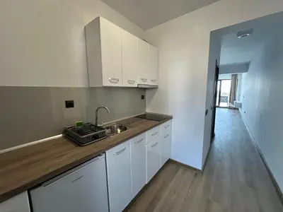a kitchen with white cabinets and a sink and a hallway at Sozopol Beach Apartments in Sozopol