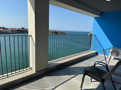 a chair on a balcony with a view of the ocean at Sozopol Beach Apartments in Sozopol