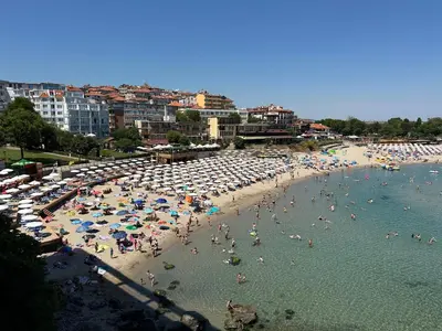 a beach with many people and umbrellas in the water at Sozopol Beach Apartments in Sozopol