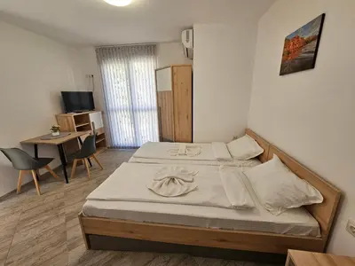 a bedroom with two beds and a desk and a television at Студио Морелия in Tsarevo