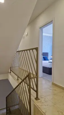 a staircase leading to a bedroom with a bed and the ocean at Геновева in Kiten