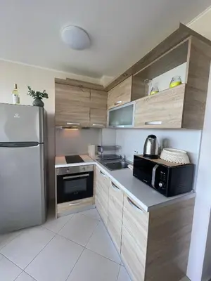 a kitchen with wooden cabinets and a stainless steel refrigerator at Byla Sea side Apartament in Byala