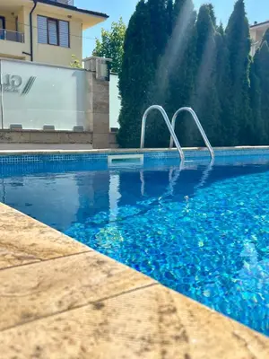 a swimming pool with a water fountain in front of a house at Byla Sea side Apartament in Byala