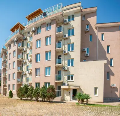 a large building with trees in front of it at Sunny Holiday Apartments in Sunny Beach