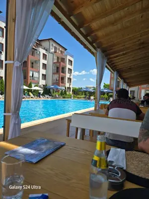 a person sitting at a table next to a swimming pool at Elia Relax & Lux in Aheloy