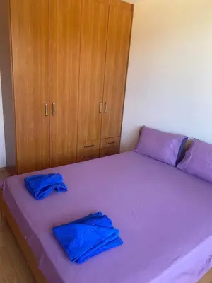 a bedroom with a purple bed with blue sheets and wooden cabinets at Pool View, 2 Bedroom Apartment in Sunny Beach