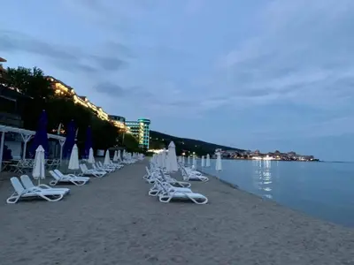 a row of lounge chairs and umbrellas on a beach at Grand rezort Marína Beach in Sveti Vlas