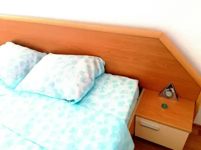 a bed with a wooden headboard and two pillows at Apartment Stoyanovi in Primorsko