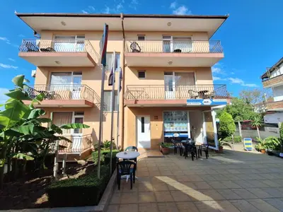 a building with tables and chairs in front of it at Къща за гости Авеню in Ravda
