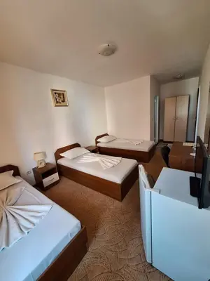 a hotel room with two beds and a television at Къща за гости Авеню in Ravda
