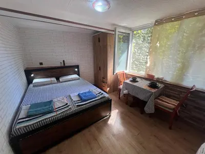 a bedroom with a bed and a table and a window at Studio Vili 2 in Varna City