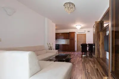a living room with a white couch and a kitchen at Boutique Apart Hotel Versis in Sunny Beach