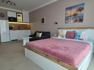 a bedroom with a large bed and a kitchen at Verano Deluxe Studios in Burgas City