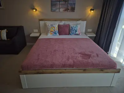 a bedroom with a large bed with a red blanket at Verano Deluxe Studios in Burgas City