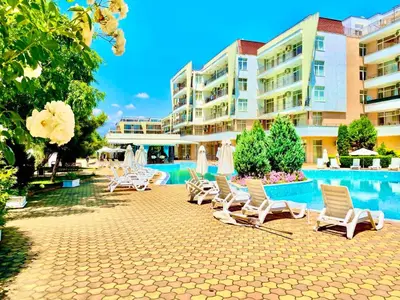 a group of chairs and a swimming pool in front of a building at Apartcomplex Grand Kamelia Sunny Beach in Sunny Beach