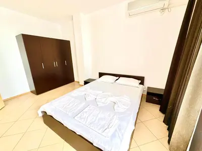 a bedroom with a bed with white sheets on it at Apartcomplex Grand Kamelia Sunny Beach in Sunny Beach