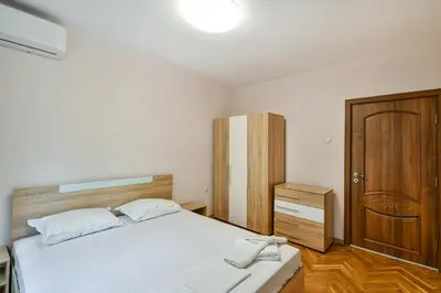 a bedroom with a bed and a wooden cabinet at Central location 2BR - 6 guests in Varna City
