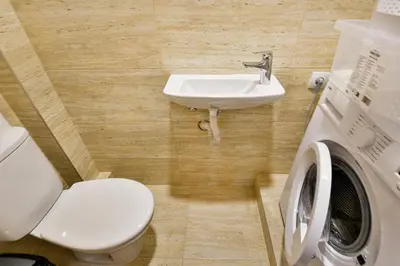 a bathroom with a toilet and a sink and a washing machine at Central location 2BR - 6 guests in Varna City