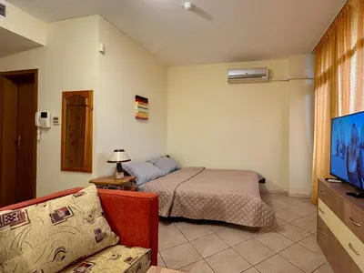 a bedroom with a bed and a couch and a tv at Prime Location Studio Midia Beach in Sunny Beach