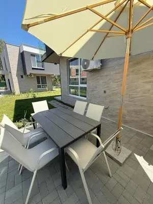 a wooden table with white chairs and an umbrella at Aurum Villas Smokinya Beach 3 in Sozopol