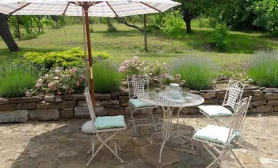 a table and chairs with an umbrella and some flowers at Bulgarian country house near the sea in Banya