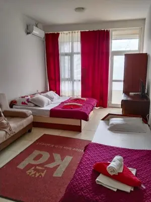 two beds in a room with red curtains at Партерни студия без обособен балкон ул Т Светослав 5 и ул България in Pomorie