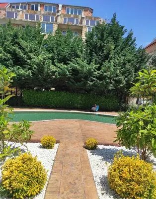 a person sitting on a bench in a garden at Blue Beach Apartments - Melia in Ravda