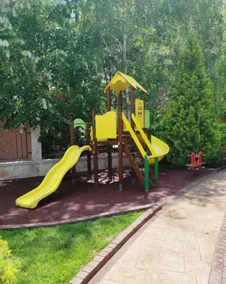a playground with a yellow slide in a yard at Blue Beach Apartments - Melia in Ravda