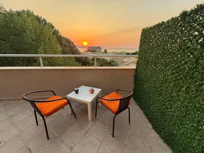 a table and two chairs on a balcony with the sunset at TROPIC BEACH apart in Sunny Beach
