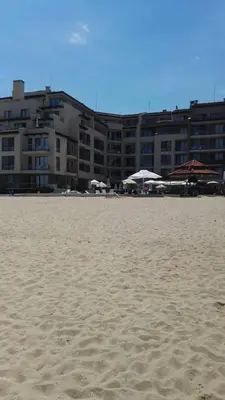 a sandy beach with a large building in the background at Panoramic sea view at the beach in Obzor