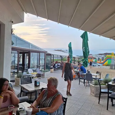 a group of people sitting on a patio near the beach at Panoramic sea view at the beach in Obzor