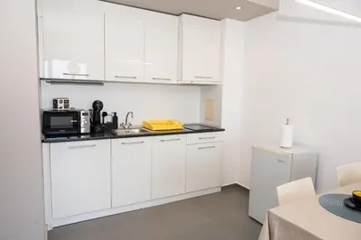 a white kitchen with white cabinets and a refrigerator at Paradise View Guest Apartment in Sozopol