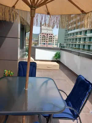 a table and chairs on a balcony with an umbrella at Силви Съни Бийч Плаза in Sunny Beach