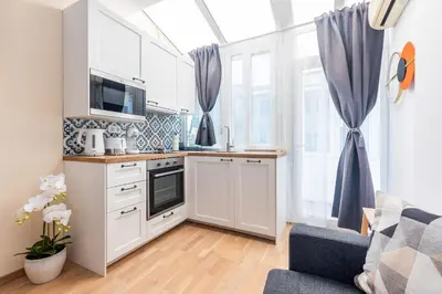 a kitchen with white cabinets and a blue couch at California in Varna City