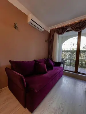 a purple couch in a living room with a window at Monte Carlo Vaio - 1BR Garden Apt - With Direct Pool Access in Sunny Beach