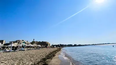 a sandy beach with umbrellas and the ocean at Luxurious Apartment with sea view in Pomorie