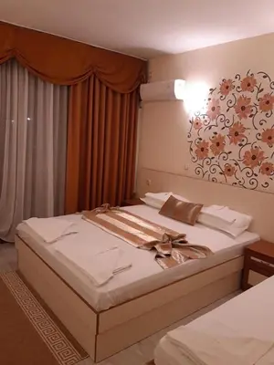 a bedroom with two beds and a flower picture on the wall at Семеен хотел Вермона in Primorsko