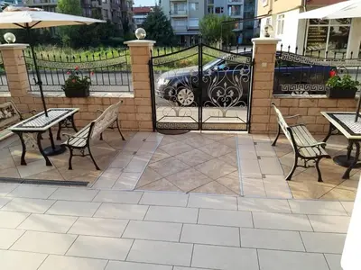 a patio with tables and chairs and an iron fence at Семеен хотел Вермона in Primorsko