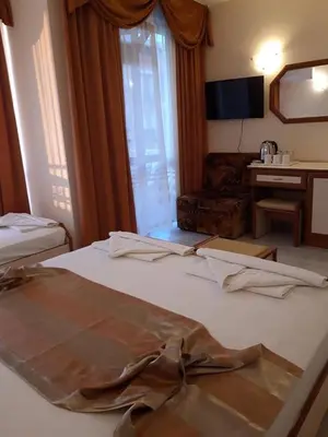 a hotel room with two beds and a desk at Семеен хотел Вермона in Primorsko