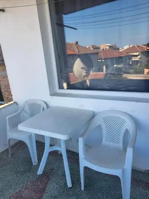 a table and two chairs in front of a window at Апартамент Стоянови in Primorsko