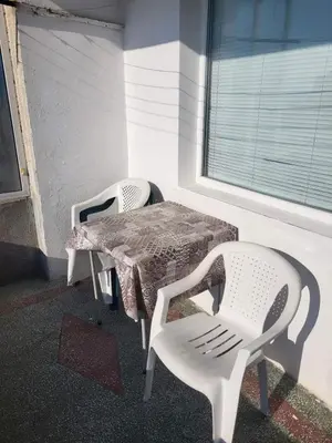two white chairs and a table and a window at Апартамент Стоянови in Primorsko