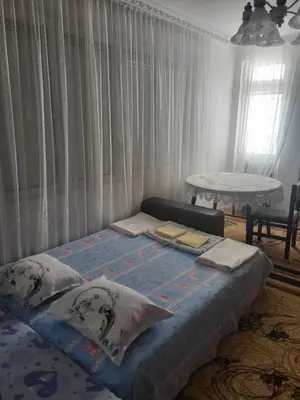 a bed in a bedroom with curtains and a table at Апартамент Стоянови in Primorsko